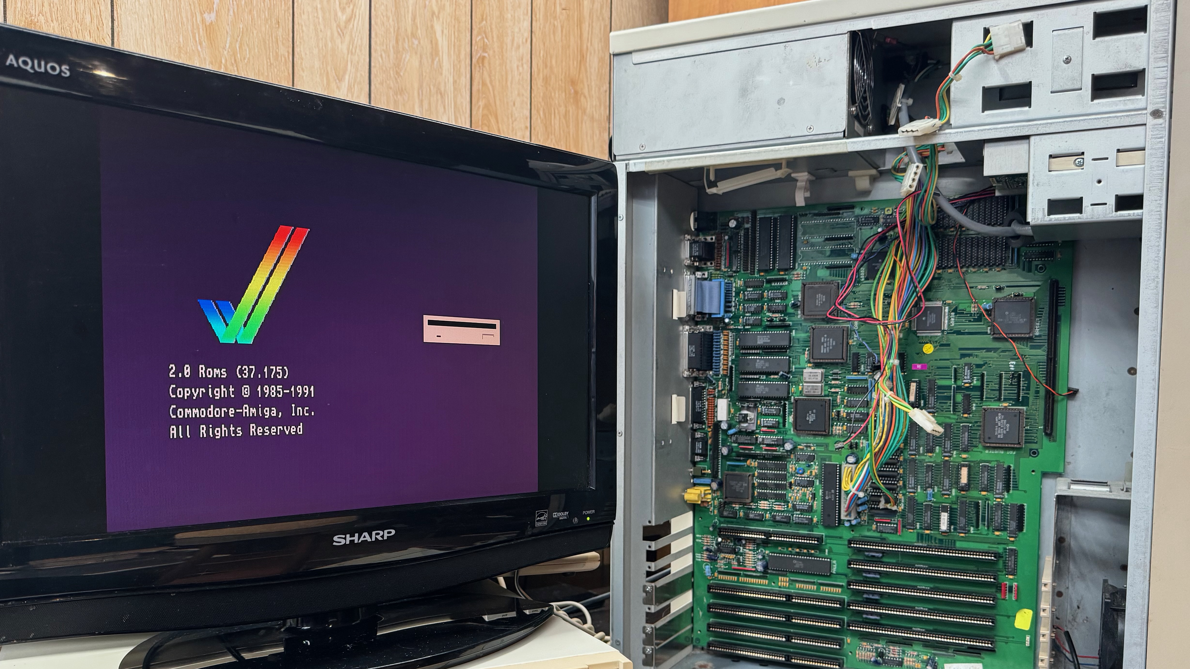 A tower computer, opened, with its motherboard exposed, showing a screen on a monitor that is asking for a 3.5" floppy disk to be inserted